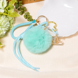 Detailed shot of mint green faux fur pompom keychain with a rhinestone letter E pendant