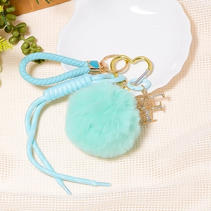 Detail of mint green leather keychain with fluffy fur ball and sparkling rhinestone letter F