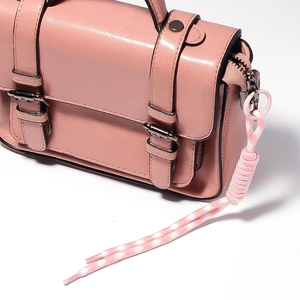Detail of pink vintage crossbody bag featuring polished faux leather and knotted charm