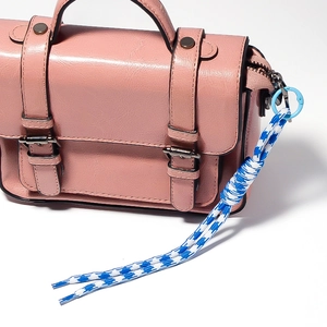 Pink faux leather crossbody bag featuring a blue woven rope keychain and silver buckles