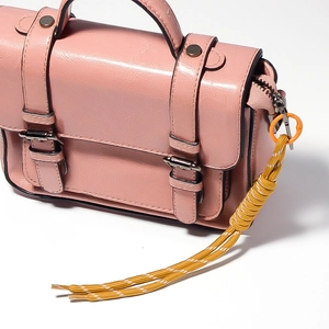 Close-up of pink vintage handbag with micro-cracked texture and yellow braided rope tassel