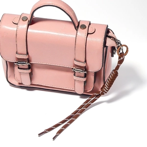 Pink PU leather crossbody bag featuring dual metal buckles and a braided cord charm detail