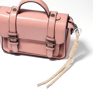 Detailed view of the knotted rope charm and metal ring on the pink leather crossbody bag