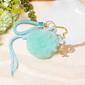 Detail of mint green faux fur pompom keychain with rhinestone letter P and butterfly