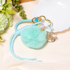 Close-up of butterfly rhinestone pendant with blue woven lanyard and mint faux fur pompom