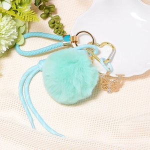 Detail of mint green pompom keychain with butterfly pendant and leather strap