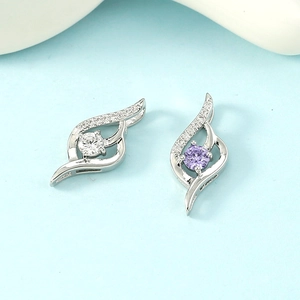Sparkling silver leaf pendant set with purple and white zircon gemstones on blue surface