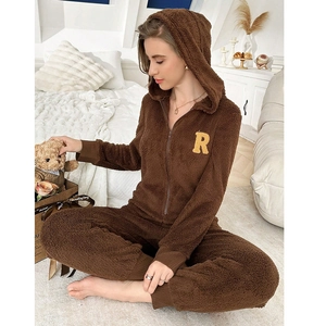 Detail of dark brown plush jumpsuit featuring a zip front and letter R applique