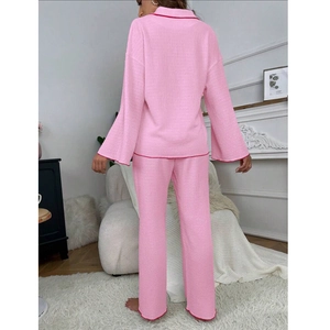 Pink two-piece women's pajama set with red piping and lapel collar, back view of model