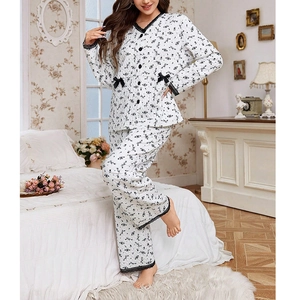 Close-up of quilted floral pajamas featuring black lace trim and bow details on white fabric