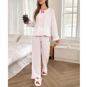 Détail du pyjama blanc avec des finitions à volants roses et un nœud sur l'encolure
