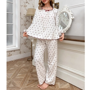 Women's sweet cherry print pajama set with long sleeves and red bow detail in home setting