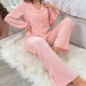 Pink two-piece pajama set with long sleeves, ruffle lace trim, and textured seersucker fabric
