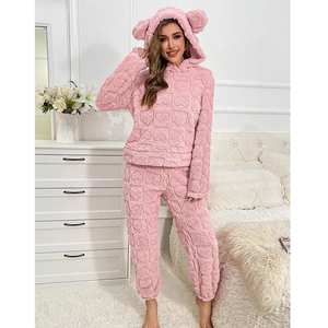 Detail of pink coral fleece pajamas featuring embossed heart patterns and bear ear hood