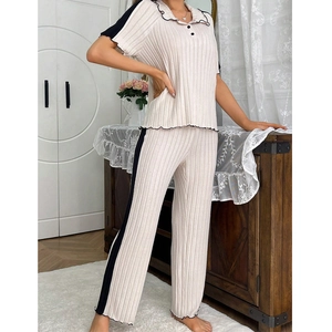 Close-up of beige ribbed pajamas with black scalloped contrast edges and pleated texture