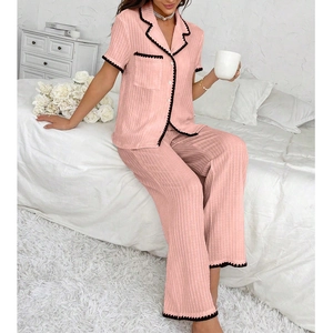 Detail of pink striped pajamas set featuring black wavy trim and soft knit fabric texture