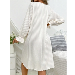 White ribbed long sleeve sleepwear dress with ruffled cuffs in a cozy bedroom setting