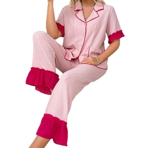 Pink two-piece pajama set with contrasting trim and ruffled cuffs on textured fabric