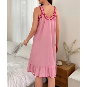 Pink sleeveless nightdress with ruffled red edges shown in a cozy bedroom scene