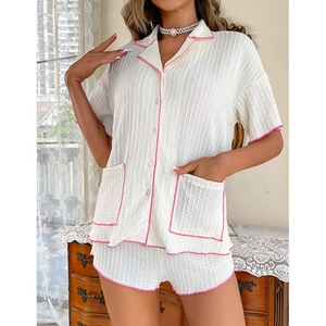 Vue détaillée du tissu crêpe texturé et du liseré rose contrasté sur le pyjama blanc