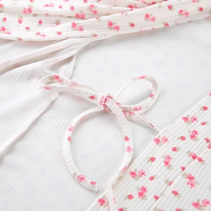 Detailed view of knitted rib fabric with pink floral print and a tied bow decoration