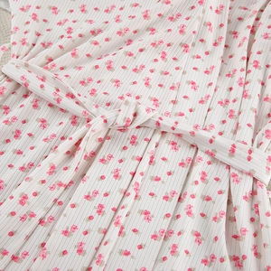 Detailed macro view of white ribbed knit fabric with pink floral print and a matching sash belt