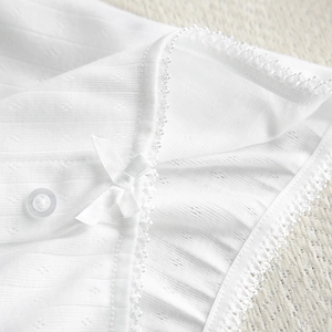 Macro shot of white ribbed knit fabric with delicate lace trim and a small bow detail