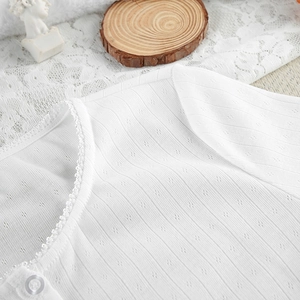 Detailed view of white knit pajama top featuring lace trim and heart pointelle texture