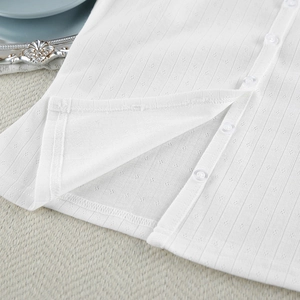 Detail of white knit pajamas showing pointelle texture and transparent buttons