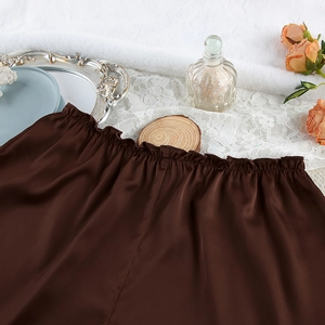 Detailed macro view of elastic gathered waist on smooth dark brown satin pajama shorts