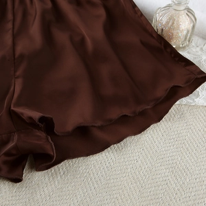 Detail of dark brown satin pajama shorts with elegant wavy edges and silky texture