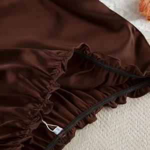 Close-up of brown satin fabric detail showing smooth texture and elastic shirred waist