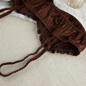 Detailed macro view of dark brown satin lingerie fabric with ruched texture and elastic edge