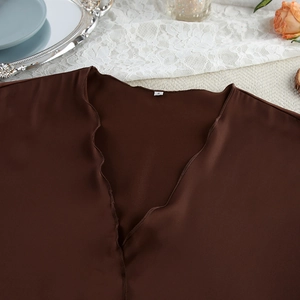 Close-up of chocolate brown satin V-neck pajama top with detailed stitching and S-size label