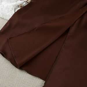 Detail of dark brown satin loungewear with smooth texture and side slit craftsmanship