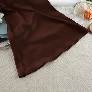 Detailed view of glossy dark brown satin fabric texture among cozy home decor props