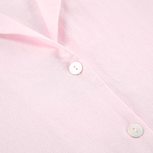 Détail du haut de pyjama rose en coton avec volants, col à revers et boutons perles