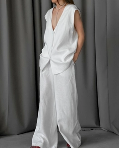 Detail eines weißen Baumwoll-Sets aus Weste und weiter Hose mit Knopfstruktur