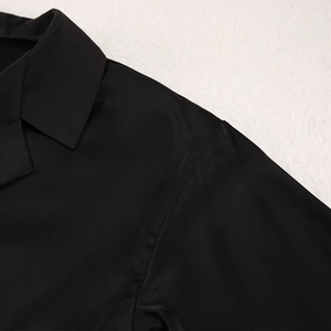 Vue détaillée du col à revers et de la texture satinée d'un haut de pyjama en soie noire