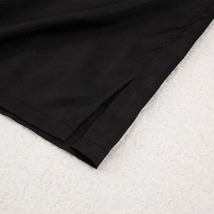 Détail de la fente latérale sur le pantalon de pyjama en soie noire sur fourrure blanche