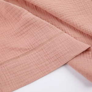 Close-up of pink double-layer cotton gauze fabric with neat double-stitched hem and texture