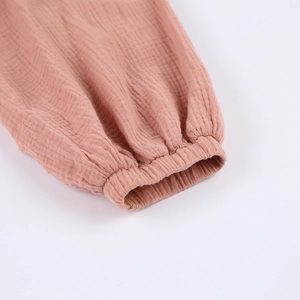 Macro detail of breathable cotton gauze cuff with elastic wrist on dusty pink bathrobe