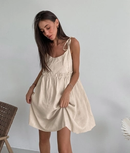 Detail of cotton linen slip dress featuring delicate shoulder straps and ruffled high waist