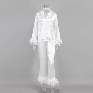 Détail du pyjama en satin blanc avec poignets en plumes d'autruche et texture soyeuse