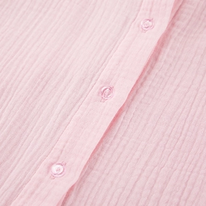Macro-opname van roze pyjama met ruches, knopen en verticale kreukelige textuur