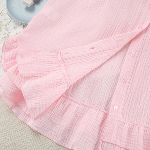 Detail van roze katoenen pyjamaset met doorschijnende knopen en ruches aan de zoom