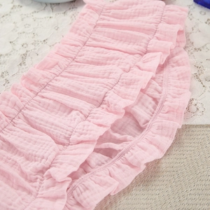 Detailopname van roze katoenen babybroekjes met ruches op wit kant