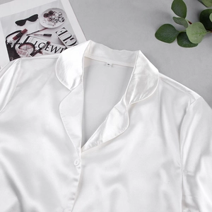 Détail de pyjama en soie blanche avec col à revers et étiquette taille M sur fond chic