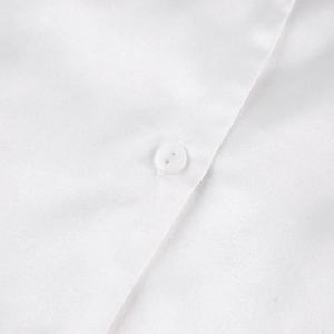 Gros plan détaillé sur la texture de soie blanche et le bouton du pyjama de luxe