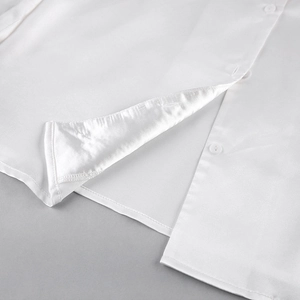 Gros plan d'un pyjama blanc en soie glacée montrant les boutons et le satin lisse